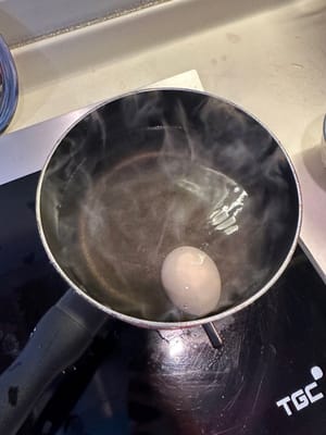 Sobald das Wasser kocht, den Herd ausschalten und eine Tasse kaltes Wasser in den Topf gießen. Sofort ein Ei hineingeben. Den Deckel schließen und 15 Minuten kochen lassen.