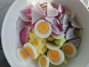 Versare il cetriolo tritato, la cipolla e le uova nel purè di patate e mescolare bene.