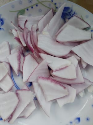 Tagliare 100 grammi di cipolla a triangoli e disporli su un piatto per un utilizzo successivo.