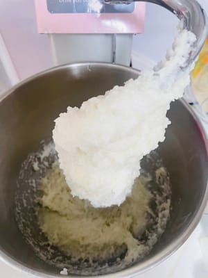 Klebreis mischen
1. Den Reis niemals direkt mit den Händen kneten, er ist heiß! Den gedämpften Klebreis schnell in die Rührschüssel einer Küchenmaschine geben, solange er noch heiß ist (er ist klebrig; kalt wird er hart). Den Knethaken anbringen und auf niedriger Stufe kneten.
~Wenn du keine Küchenmaschine hast, verwende ein großes, hitzebeständiges Gefäß und etwas wie ein Nudelholz. Lass deine Hände nicht direkt mit dem heißen Reis in Berührung kommen! Er wird so heiß, dass er an deinen Händen klebt, und du verbrennst sie so stark, dass du sie nicht einmal abschütteln kannst. 😂
Ob mit der Maschine oder von Hand: Knete etwa 6–8 Minuten kräftig, bis der Reis klebrig und fest wird. Je stärker du rührst, desto besser! Wenn du es mit der Hand machst, lohnt sich die Mühe; das köstliche Essen lockt!