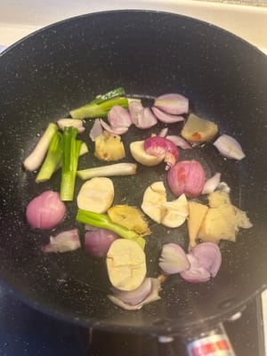 Eine Pfanne erhitzen und Ingwer, Frühlingszwiebeln, Knoblauch und Schalotten darin anbraten, bis sie duften. Shiitake-Pilze hinzufügen und unter Rühren braten, bis die Flüssigkeit verdampft ist. Das Einweichwasser der Shiitake-Pilze dazugeben.