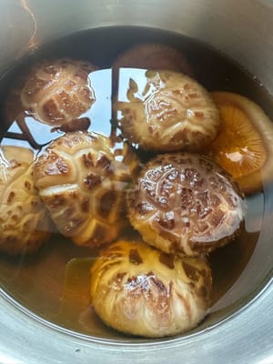 Shiitake-Pilze mit etwas Speiseöl einweichen, damit sie elastischer werden. Das Einweichwasser nicht wegschütten, sondern zum Schmoren der Pilze verwenden.