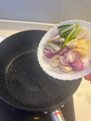 Eine Pfanne erhitzen und Ingwer, Frühlingszwiebeln, Knoblauch und Schalotten darin anbraten, bis sie duften. Shiitake-Pilze hinzufügen und unter Rühren braten, bis die Flüssigkeit verdampft ist. Das Einweichwasser der Shiitake-Pilze dazugeben.