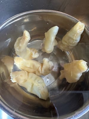 Die Fischblase mit Ingwer, Frühlingszwiebeln und Kochwein 10 Minuten blanchieren. Anschließend sofort mit kaltem Wasser abspülen.