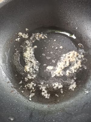 Eine Bratpfanne vorbereiten, das Öl hineingeben, warten bis es heiß ist, dann den Knoblauch dazugeben.