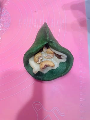 (2) Füllen und Formen: Nehmen Sie einen lockeren Teigball, drücken Sie ihn mit der Handfläche flach und rollen Sie ihn zu einem Kreis aus. Geben Sie die Mochi-Füllung und die gehackten Nüsse in die Mitte und drücken Sie die Öffnung von einem Ende zur Mitte hin fest zusammen (drücken Sie mehrmals, damit die Füllung beim Backen nicht ausläuft). Alternativ können Sie den Teig auch nach Belieben formen.

Tipp: Falls Sie nicht wissen, wie man rollt oder faltet, schauen Sie sich einfach das Video an, das ich gepostet habe; die Schritte sind ganz einfach!