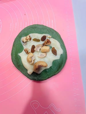 (2) Füllen und Formen: Nehmen Sie einen lockeren Teigball, drücken Sie ihn mit der Handfläche flach und rollen Sie ihn zu einem Kreis aus. Geben Sie die Mochi-Füllung und die gehackten Nüsse in die Mitte und drücken Sie die Öffnung von einem Ende zur Mitte hin fest zusammen (drücken Sie mehrmals, damit die Füllung beim Backen nicht ausläuft). Alternativ können Sie den Teig auch nach Belieben formen.

Tipp: Falls Sie nicht wissen, wie man rollt oder faltet, schauen Sie sich einfach das Video an, das ich gepostet habe; die Schritte sind ganz einfach!