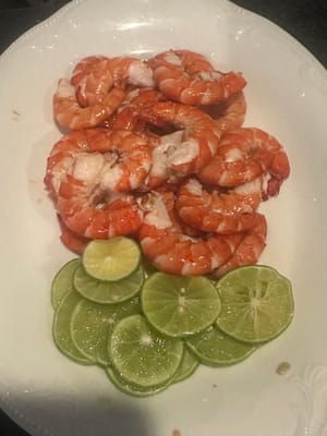 จัดกุ้งปอกเปลือกและมะนาวฝานลงในจานเสิร์ฟ