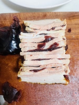 Distribuire uniformemente la pasta di fagioli rossi al centro di ogni fetta di carne ancora attaccata al taglio.