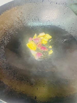 鍋裡留少許底油，放入料頭（大蒜、薑片、洋蔥 ），開小火慢慢爆香，炒到洋蔥變軟、香味出嚟，再倒入青紅彩椒塊，轉中火翻炒至彩椒微微變軟 。
