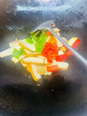 Leave a little oil in the pan, add the ingredients (garlic, ginger, onion), slowly sauté over low heat until the onion becomes soft and fragrant, then pour in the green and red pepper pieces, turn to medium heat and stir-fry until the peppers are slightly softened.