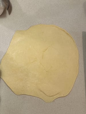 擀成一個扁平的大圓餅，不要太薄（約0.5公分厚）。