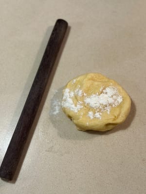 將麵團放在擀麵棍上，撒上少許麵粉以防沾黏。