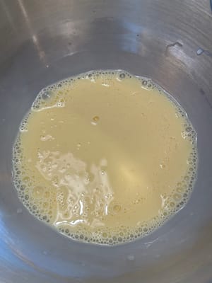 首先，在一個攪拌碗中，將雞蛋和溫牛奶混合均勻。