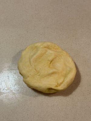 將麵團放在擀麵棍上，撒上少許麵粉以防沾黏。