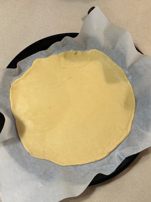 將麵糊轉移到鋪有烘焙紙的烤盤（最好是圓形烤盤）。