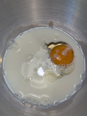 首先，在一個攪拌碗中，將雞蛋和溫牛奶混合均勻。