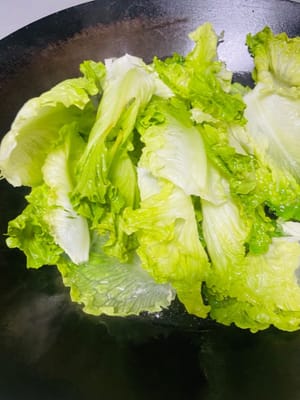 Seleccione lechuga fresca, desmenúcela pieza por pieza y enjuáguela cuidadosamente con agua corriente para eliminar el polvo y las impurezas de la superficie. Luego, colóquela en un recipiente, añada la cantidad adecuada de agua, espolvoree con una cucharadita de sal, remueva bien y deje la lechuga en remojo en agua salada durante 10 minutos para esterilizarla y eliminar los residuos de pesticidas. Después del remojo, escurra la lechuga en una cesta de drenaje y reserve.
