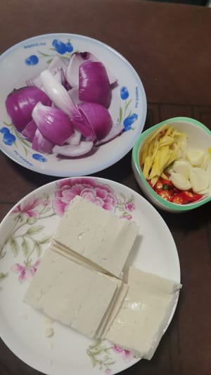 หั่นขิงเป็นเส้นบางๆ หั่นต้นหอมเป็นท่อนยาวๆ และหั่นเต้าหู้เป็นชิ้นๆ สับหัวหอมครึ่งหัวเป็นชิ้นใหญ่ๆ และสับพริกและกระเทียมเป็นชิ้นเล็กๆ