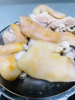 Escaldar para eliminar el olor a pescado. Colocar las patas de cerdo lavadas en una olla con agua fría, añadir unas rodajas de jengibre, un poco de vino de cocina y un puñado de granos de pimienta (o cebolletas). Cuando el agua hierva, cocinar durante 5 minutos para eliminar la espuma de sangre. Retirar, enjuagar con agua tibia y escurrir.