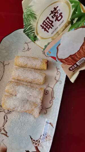 巻き終わったらお皿に盛り、白いココナッツパウダーと細かいココナッツパウダーを振りかけます。2回巻くことでココナッツパウダーが均等に付着し、より美味しくなります。