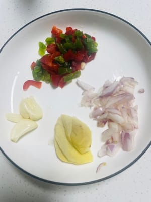 Preparare gli ingredienti: tritare la cipolla, schiacciare e tritare l'aglio, affettare lo zenzero e tagliare a dadini i peperoni verdi e rossi che utilizzeremo in seguito.