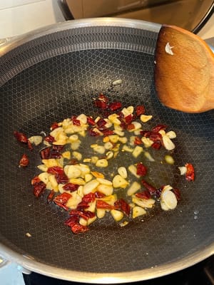 aggiungere i fiocchi di peperoncino e continuare a rosolare fino a quando non saranno leggermente carbonizzati