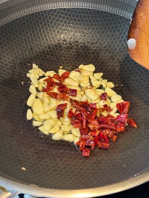 aggiungere i fiocchi di peperoncino e continuare a rosolare fino a quando non saranno leggermente carbonizzati