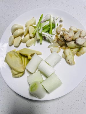 Iris lengkuas menjadi irisan tipis atau potongan kecil agar lebih mudah mengeluarkan rasa. Potong daun bawang menjadi beberapa bagian diagonal agar aromanya lebih merata. Pipihkan bawang putih, potong daun bawang menjadi beberapa bagian, dan potong irisan jahe sedikit lebih tebal agar tidak gosong saat digoreng.