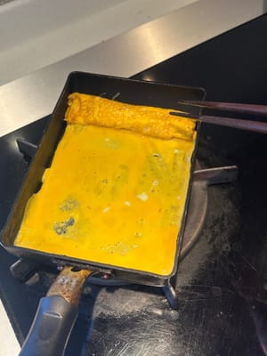 完成後，將折疊好的蛋捲推到頂部，再鋪上一層蛋液。如果喜歡，也可以在這裡加入芝士。