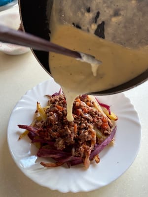 Finally, assemble the dish by layering the mince on the fries, and pour the cheese sauce over to finsih