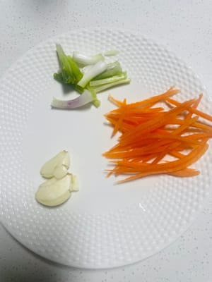 corta la cebolleta en gajos de 3 cm de largo; aplana el ajo con un cuchillo; corta las zanahorias en tiras muy finas para decorar; usa poca cantidad; si te gusta el picante, usa pimiento rojo rallado en su lugar.