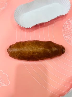 包餡整形:
取一個鬆弛好的麵團擀開,麻薯也擀薄點(比面皮小一圈就行),鋪在麵團上,撒上愛吃的堅果,再塞3-4個法芙娜巧克力幣(我主打一個摳搜,只放3個也超香!)。接著捲緊捲實,別讓餡料半路「離家出走」~