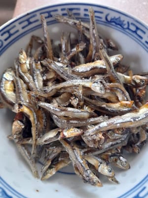 将凤尾鱼略煎，然后取出备用。爆香蒜蓉和红葱头。加入辣椒片和南姜，翻炒均匀。