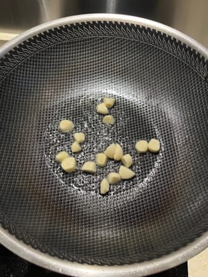 Calienta la sartén y vierte el ajo picado en el aceite.