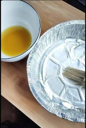 先把香蕉去皮切成瓶盖厚度大小。准备一个耐高温的容器，刷上少许底油，均匀的铺上香蕉片。
