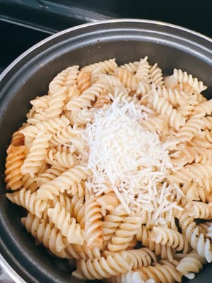 Die Nudeln ungewaschen in den Topf geben, etwas Butter, geriebenen Käse und italienische Gewürze hinzufügen und 1–2 Minuten unter Rühren anbraten. Sollten die Nudeln etwas trocken sein, können Sie 1–2 Löffel der Nudelsuppe hinzufügen.