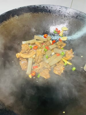 In einem anderen Wok etwas Öl erhitzen und die gewürfelten grünen und roten Chilischoten sowie den gehackten Knoblauch anbraten. Die geschmorte Ente hinzufügen und vor dem Servieren kurz anbraten.
