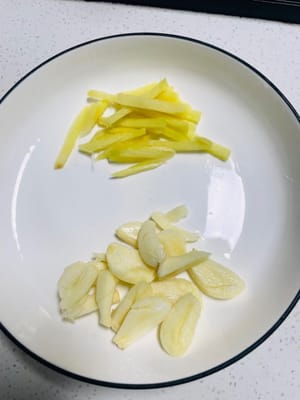 Ingwer in Scheiben oder Streifen schneiden, Knoblauch zerdrücken und fein hacken. Grüne und rote Chilischoten klein schneiden. Für später beiseitestellen.