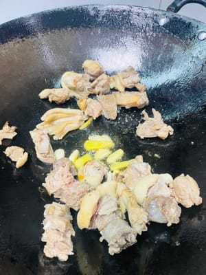 Ingwer und Knoblauch anbraten, bis sie duften:
Die gebratene Ente an den Rand des Woks schieben. Hitze reduzieren. Den gehackten Knoblauch und die Ingwerscheiben in die Mitte geben und anbraten, bis sie duften.