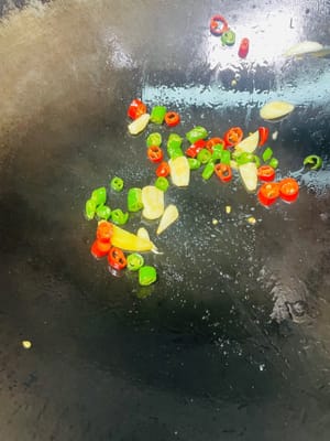 In einem anderen Wok etwas Öl erhitzen und die gewürfelten grünen und roten Chilischoten sowie den gehackten Knoblauch anbraten. Die geschmorte Ente hinzufügen und vor dem Servieren kurz anbraten.