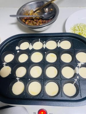 반죽 붓기: 작은 구멍에 반죽을 반쯤 채우고, 양념한 새우와 오징어 다리를 넣은 다음, 다진 양파와 다진 양배추를 넣습니다.