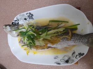 将葱放在鱼上面，然后倒入热油。