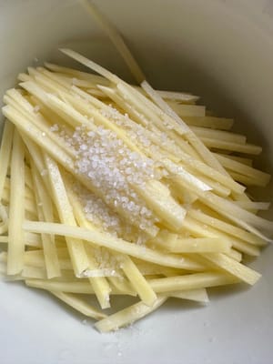 Cut the potatoes into thin strips and add a little salt.