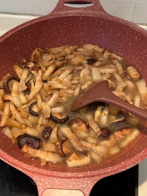 Aggiungere i funghi shiitake e soffriggere insieme. Dopodiché, versare l'acqua dei funghi shiitake fino a quando non si sarà allineata con gli ingredienti.