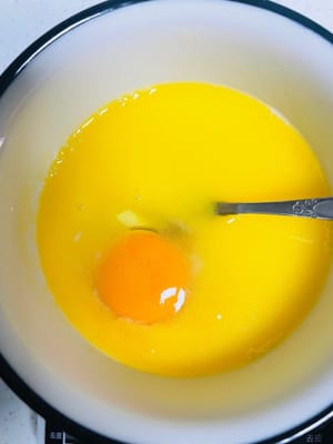 ใส่ไข่: ตอกไข่ลงในส่วนผสมแล้วคนให้เข้ากันจนไข่และนมข้นหวานเข้ากันดี