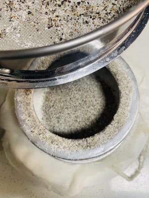 1. Die Hälfte des restlichen Pulvers auf das Käsetuch in der Form sieben.

2. Die Mischung aus schwarzem und weißem Sesampulver zusammen sieben und als zweite Schicht verwenden.

3. Die restliche Klebreismehlmischung in die Form sieben.

Diesen Vorgang insgesamt dreimal wiederholen. Die Form nach jeder Schicht leicht schütteln, um die Oberfläche zu glätten. Das Pulver nicht andrücken, da es sonst zu fest wird. Dieser Vorgang erfordert etwas Geduld und dauert etwa 10 Minuten.