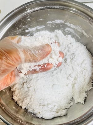 Zerdrücken Sie die Teigkugeln mit den Händen, je feiner desto besser, damit sie später problemlos durch das Sieb passieren können.