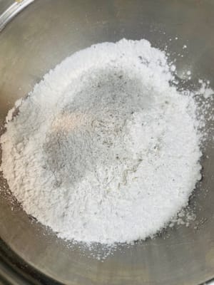 Reismehl und Klebreismehl in einen Behälter geben, Puderzucker hinzufügen (mein Puderzucker war durch schwarzes Sesampulver 