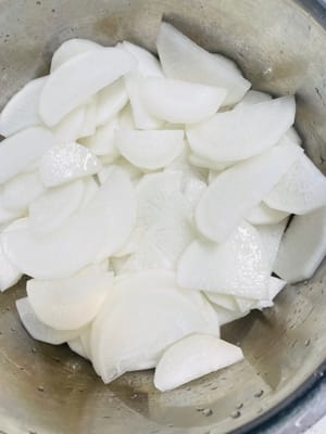 Marinasi dan Tiriskan:
Siapkan wadah bersih dan tuang lobak yang sudah ditiriskan. Tambahkan 1,5 sendok makan garam dan 1 sendok makan gula, aduk rata dengan tangan, lalu marinasi selama kurang lebih 15 menit agar lobak mengeluarkan cairannya.